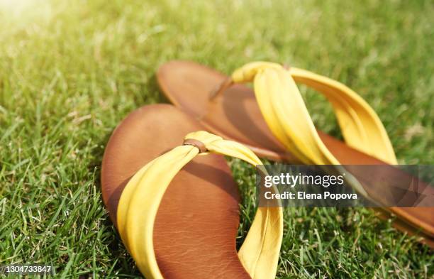 close-up yellow flip-flops on green grass - sandali stock-fotos und bilder