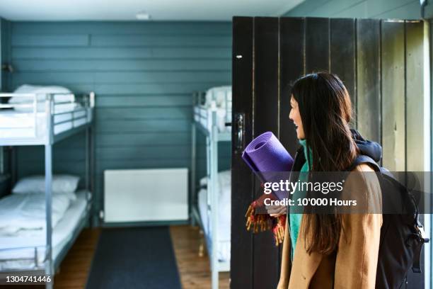 woman arriving in hostel dormitory holding yoga mat - hostel stockfoto's en -beelden