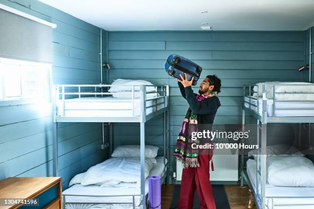 man putting suitcase on bunkbed in hostel dormitory - hostel stock pictures, royalty-free photos & images