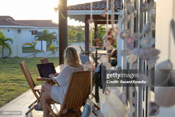de vrouw werkt op laptop buitenhuis op patio bij zonsopgang - business woman schild stockfoto's en -beelden