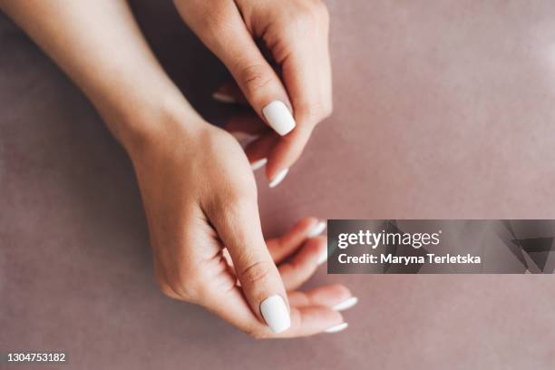 female hands with a neat white manicure on a beige background. - woman pink background stock pictures, royalty-free photos & images