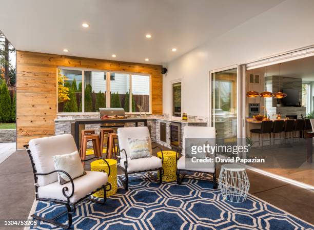 outdoor/indoor patio area with outdoor grill and outdoor chairs - downlight stock pictures, royalty-free photos & images