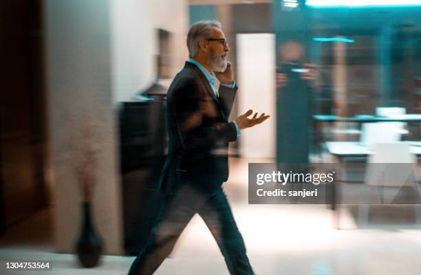 geschäftsmann telefoniert während des gehens - dark office hallway stock-fotos und bilder