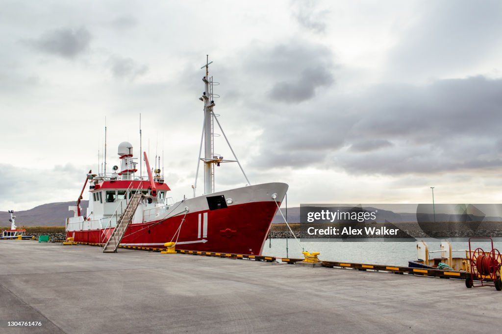 Red fishing trawler boat moored at pier