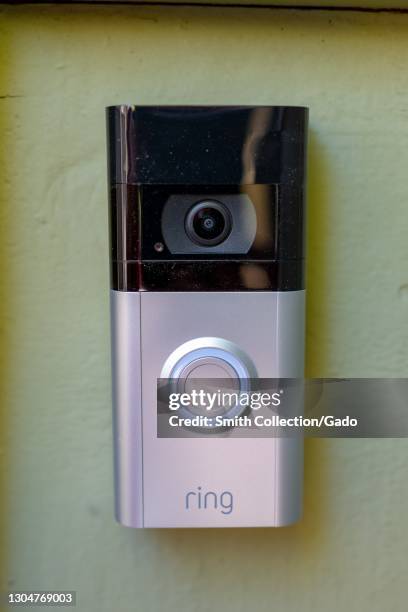 Close-up of a video doorbell with a "Ring" logo attached to a light-colored wall, February 17, 2021.