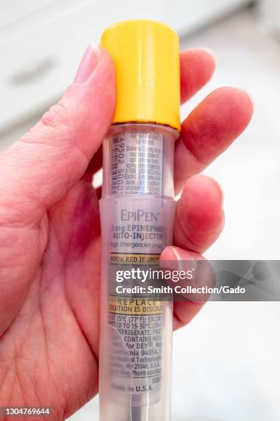 Close up of a hand holding an EpiPen branded epinephrine autoinjector, February 17, 2021.