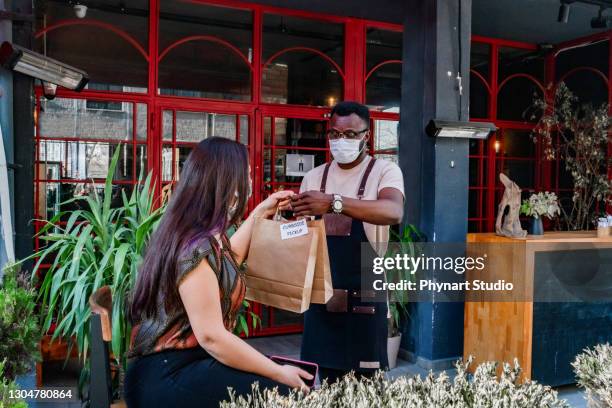 customer pick up takeout food order from waitress - picking up food stock pictures, royalty-free photos & images