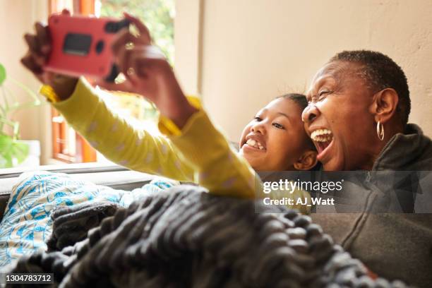 grand-mère riant et petite-fille parlant selfies ensemble à la maison - mamie grimace photos et images de collection