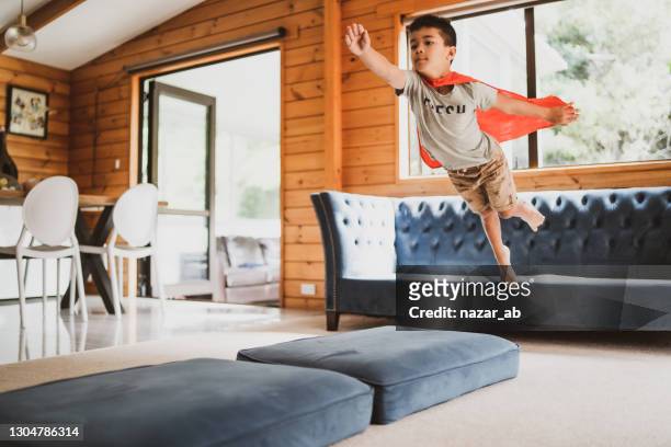 little boy jumping in mid air from sofa. - flying kiwi stock pictures, royalty-free photos & images