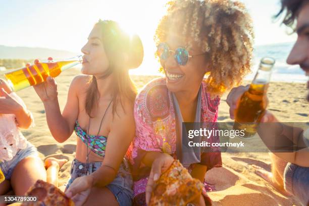 gruppe von freunden bei einem picknick mit pizza und spaß am strand bei sonnenuntergang. - tropical music stock-fotos und bilder