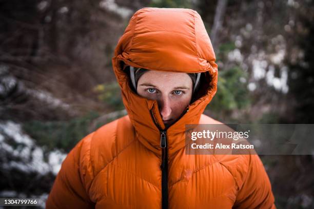 female wearing puffy down jacket with hood up - survival stock-fotos und bilder