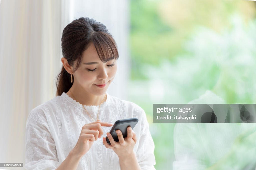 Attractive japanese woman using smart phone in the living room