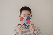 Preteen boy holding puzzle jigsaw,  child mental health concept, world autism awareness day, teen autism spectrum disorder awareness concept
