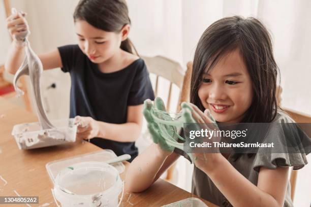 Happy mixed Asian girl friends making homemade slime toy, sensory art and craft, fun homeschool chemistry project