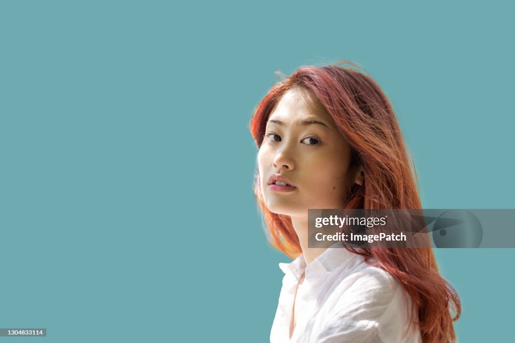 Young women looking at viewer on plain coloured background