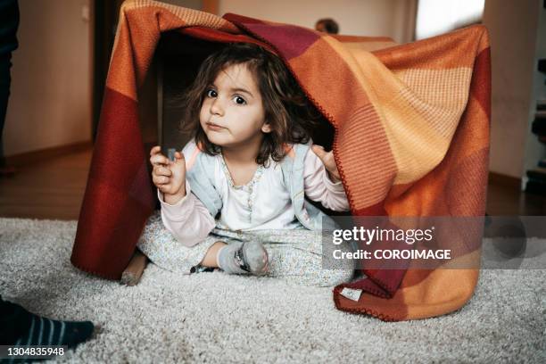 little girl sitting under a blanket hovel at home. - kids fort stock pictures, royalty-free photos & images