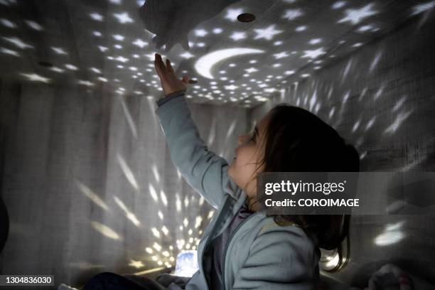 child with a night lamp projecting stars and moon at bedroom. - lamp imagens e fotografias de stock