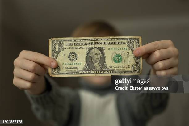 the boy holds one dollar in front of him. - dollar sign stock-fotos und bilder