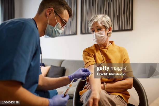 male nurse taking blood from senior woman - cateter imagens e fotografias de stock