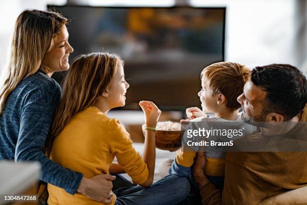 familia feliz comiendo palomitas de maíz mientras ve la televisión en casa. - familia viendo la television fotografías e imágenes de stock