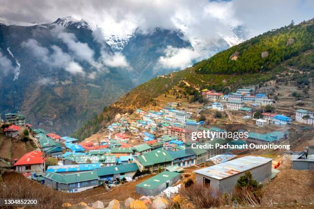 view of namche bazaar with snow capped mountain and cloudy sky - namche bazaar stock pictures, royalty-free photos & images