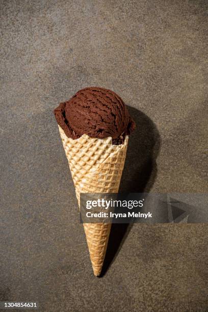 overhead shot of homemade chocolate ice cream in waffle cone on brown background. top view. - chocolate top view stock-fotos und bilder