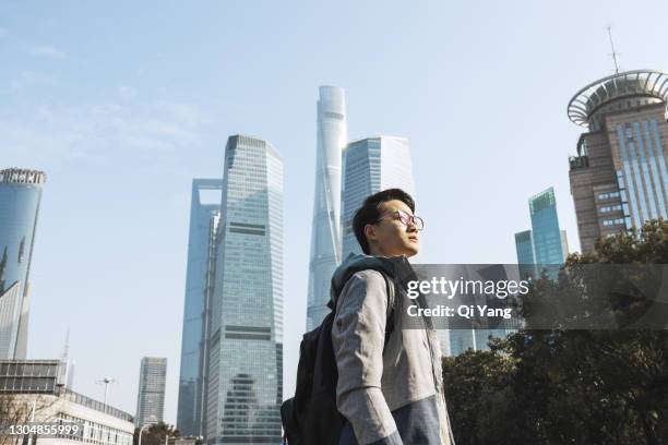 young man looking at the shanghai city skyline - shanghai business stock-fotos und bilder