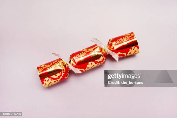 high angle view of a red and gold colored christmas cracker on purple background - christmas crackers stock pictures, royalty-free photos & images