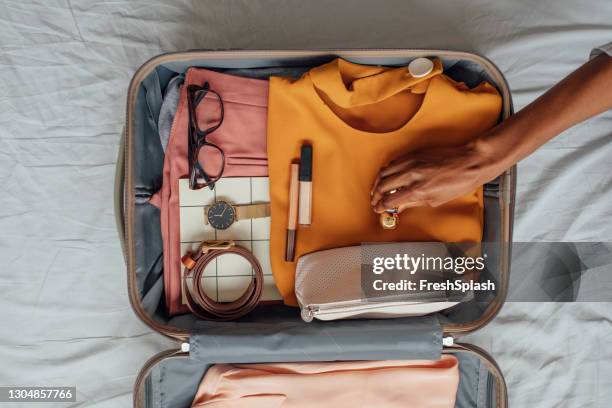 eine frau, die ihre kleidung in einem koffer packt - holiday packing stock-fotos und bilder