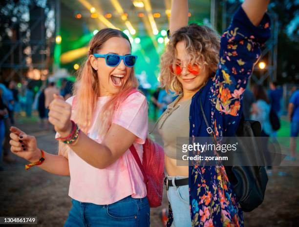 weibliche freunde tanzen und heben die arme zu guter musik auf demonstütze - festival stock-fotos und bilder