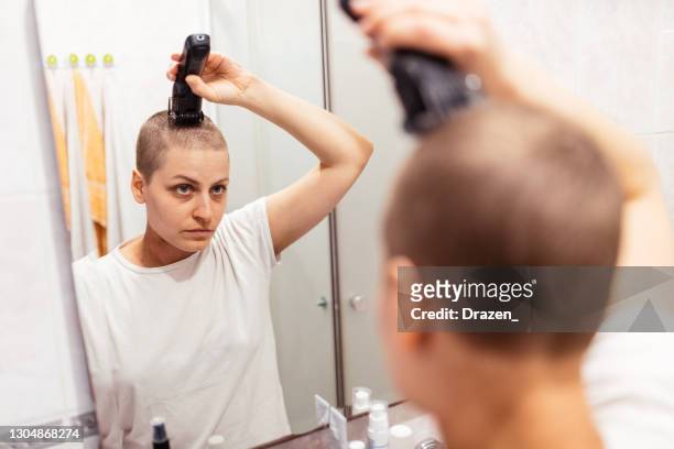 cancer survivor in bathroom shaving or trimming her hair - shaving head stock pictures, royalty-free photos & images