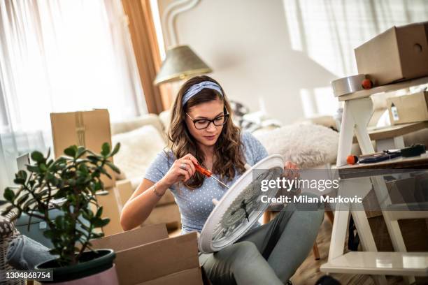 年輕女子搬到新公寓。一個年輕的美女坐在新房子的地板上。一個幸福的女人在她的新家，從箱子裡拆開東西的肖像。 - wall clock 個照片及圖片檔