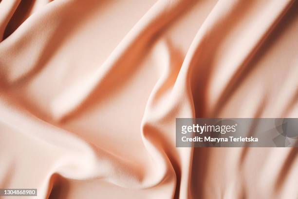 background from satin fabric of peach color. - seidentuch stock-fotos und bilder