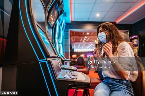 woman playing slot machine in casino - casino mask stock pictures, royalty-free photos & images