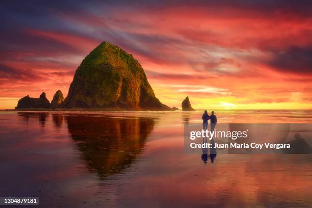 dramatic clouds caressing haystack rock at sunset - cannon beach (oregon, usa) - cannon beach foto e immagini stock