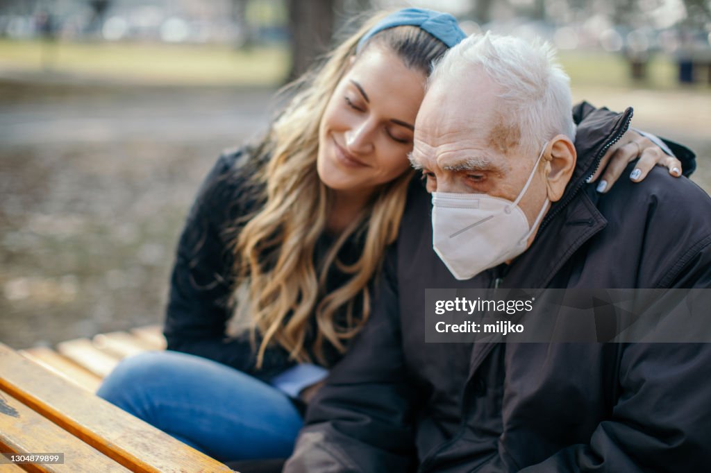 Old man and young woman sitting in park and talking