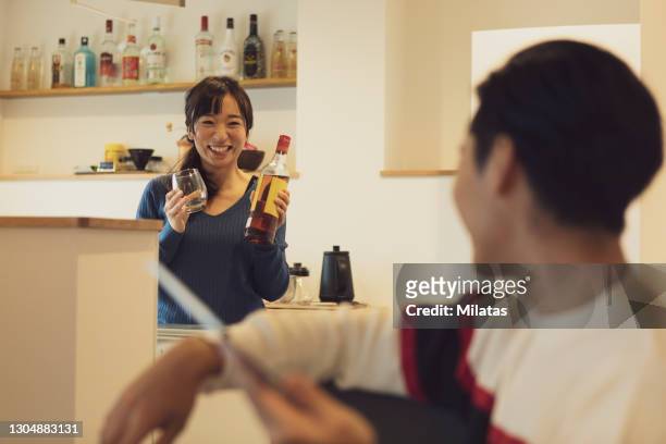 wife standing in kitchen and husband relaxing - the japanese wife foto e immagini stock