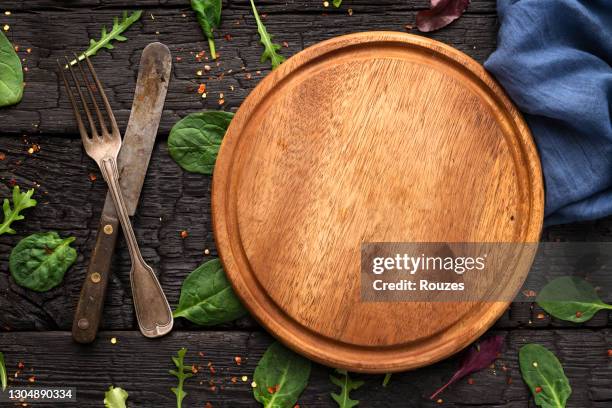 fresh leaf salad and wooden cutting board on table - round wooden chopping board stock pictures, royalty-free photos & images