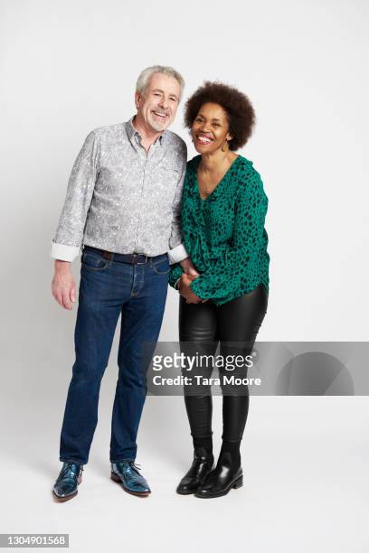 mature couple smiling against white background - aged man portrait studio stock-fotos und bilder