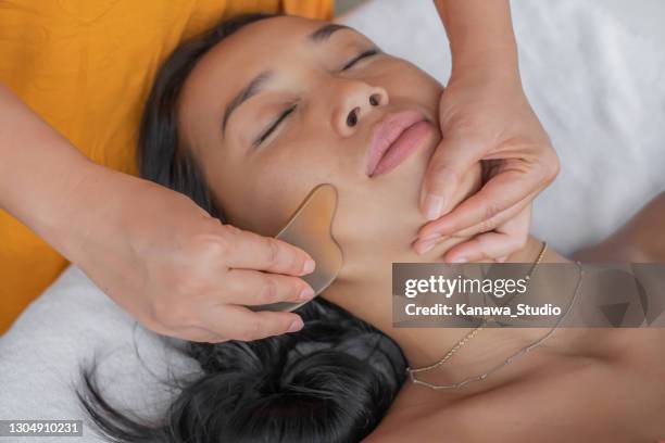 indonesian woman having facial gua sha in a health spa - spooning stock pictures, royalty-free photos & images