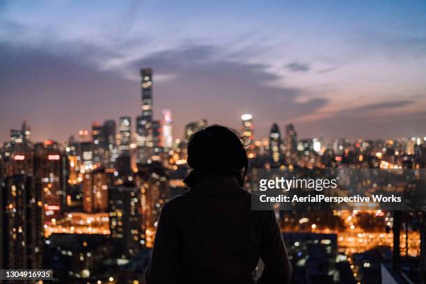 vrouw die zich voor moderne stad bij nacht bevindt - beijing tourist stockfoto's en -beelden