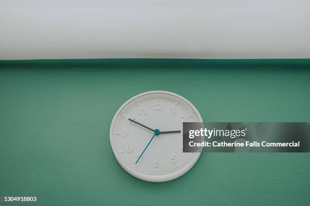 a simple white wall clock above a sunny window, in the afternoon - seconds of summer sydney photo shoot stockfoto's en -beelden