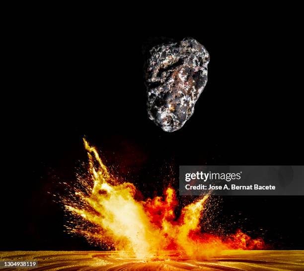 impact of meteorite, rock or stone of fire on the soil, producing an explosion and a crater of powder on a black background. - planet collision stock-fotos und bilder