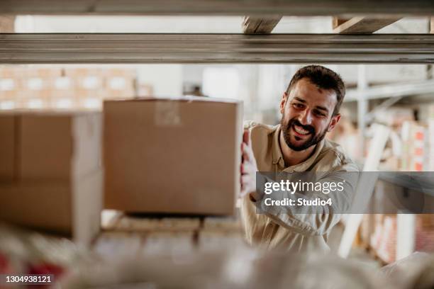 repartidor colocando una caja de cartón en un estante - cuarto almacén fotografías e imágenes de stock