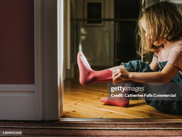 little girl pulls on a pink sock - sock stock pictures, royalty-free photos & images