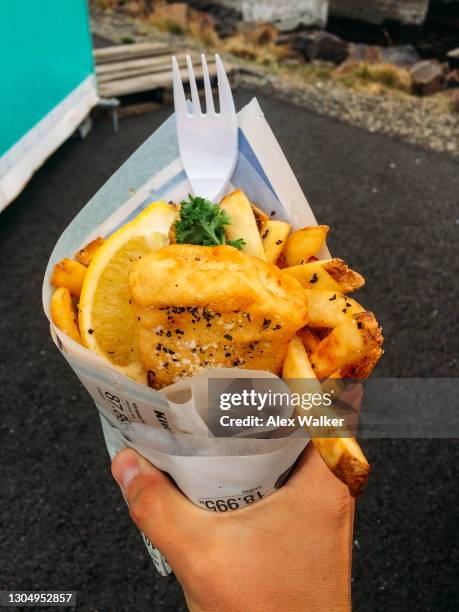 person holding fish and chips in paper cone - chips on paper stock pictures, royalty-free photos & images