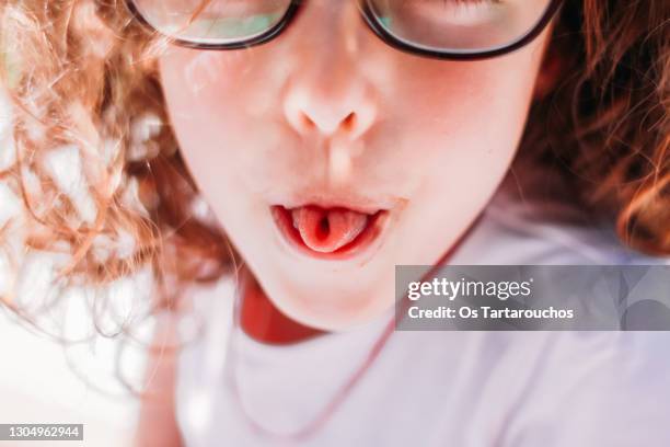 girl rolling up her tongue like an u letter - kid sticking tongue out photos et images de collection