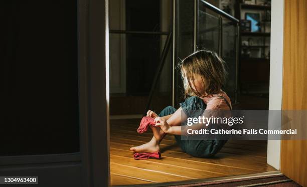 little girl pulls on a pink sock - kid changing clothes stock pictures, royalty-free photos & images