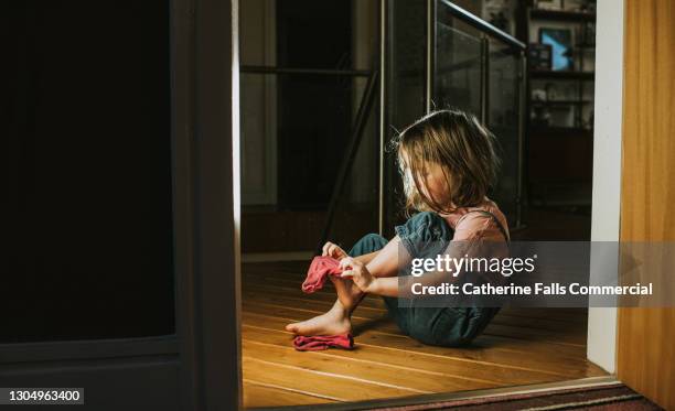 little girl pulls on a pink sock - making choice stock pictures, royalty-free photos & images