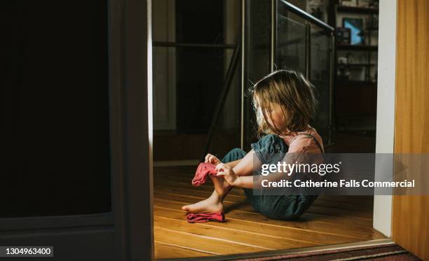 little girl pulls on a pink sock - daily sport girls bildbanksfoton och bilder
